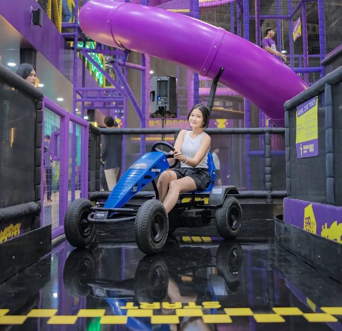 A guest enjoying a blue pedal go-kart inside a SuperPark attraction